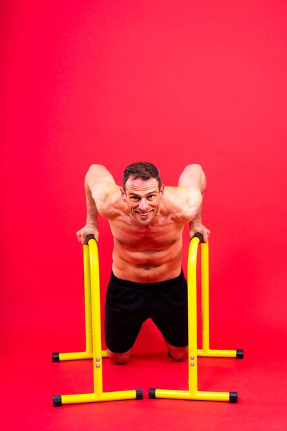 Vista frontal y lateral de una foto de un joven fuerte haciendo ejercicio en barras paralelas en el estudio