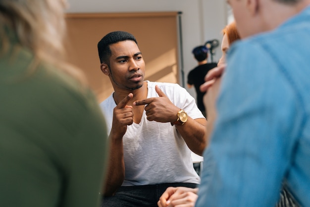 Vista frontal del líder masculino afroamericano explicando nuevas estrategias al joven equipo de negocios creativos, durante la lluvia de ideas en la sala de reuniones. Hombre de negocios discutiendo el trabajo con el equipo en la sala de juntas.