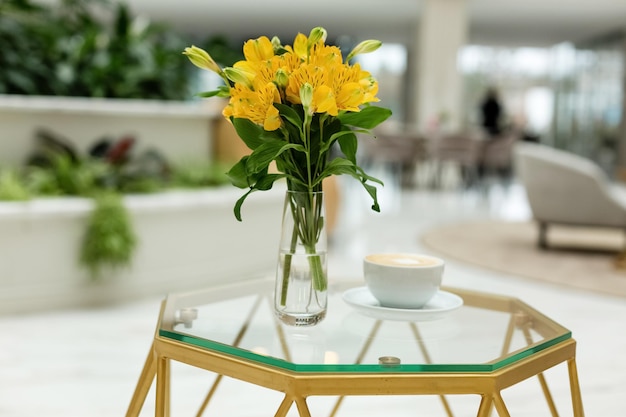 Vista frontal del lugar de trabajo taza de café ramo de flores amarillas sobre la mesa Plantas verdes Frescura Concepto creativo