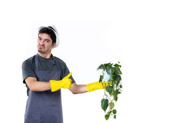 Vista frontal macho joven en guantes amarillos sosteniendo planta sobre fondo blanco hierba árbol suelo jardinero verde jardín flor color