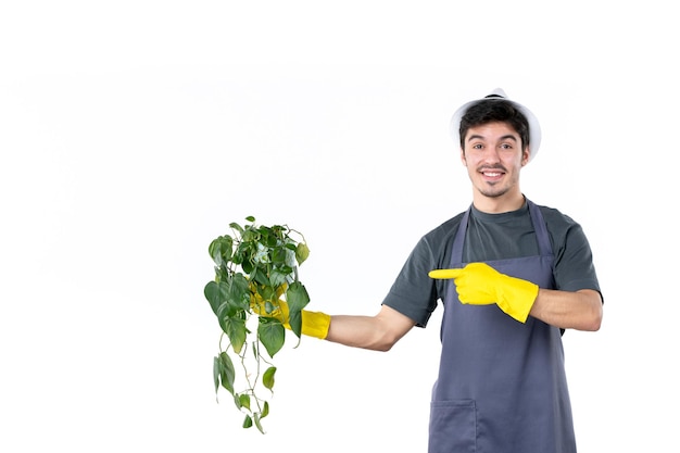 Vista frontal macho joven en guantes amarillos sosteniendo planta sobre fondo blanco hierba árbol tierra trabajo verde jardín flor color jardinero