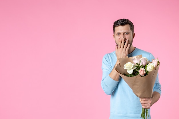 Vista frontal macho joven con ramo de flores hermosas sobre fondo rosa fecha de matrimonio parque día de la mujer marzo igualdad amor diversión sensual