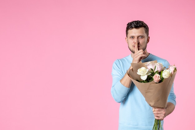 Vista frontal macho joven con ramo de flores hermosas sobre fondo rosa fecha de matrimonio parque día de la mujer marzo igualdad amor femenino sensual