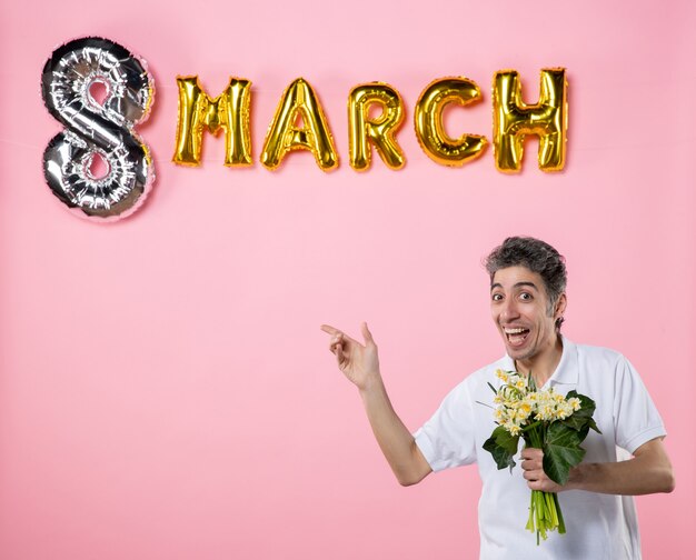 vista frontal macho joven sosteniendo flores para mujer con marzo decorado fondo rosa sensual femenino día de la mujer feriado glamour igualdad emoción