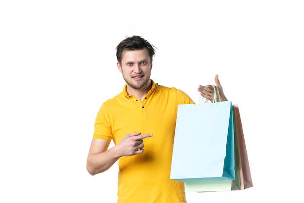 Vista frontal macho joven sosteniendo paquetes de regalo sobre fondo blanco gimnasio trabajo vendedor uniforme dinero compras salud deporte