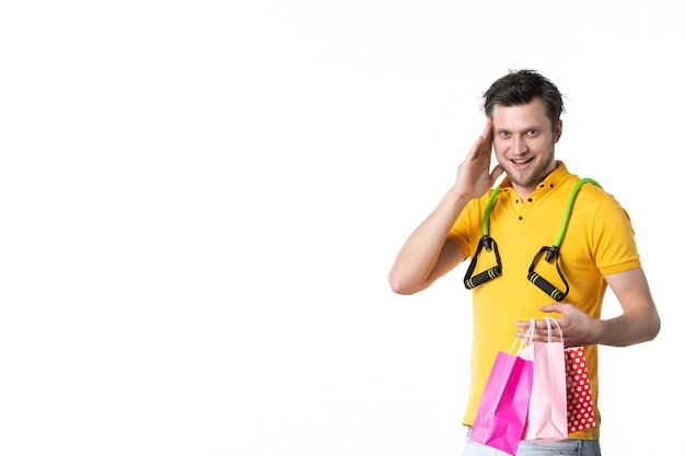 Vista frontal macho joven sosteniendo pequeños paquetes con expansor sobre fondo blanco trabajo color deporte vendedor trabajador uniforme de compras