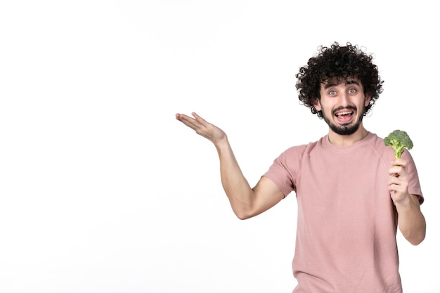 Vista frontal macho joven sosteniendo poco brócoli sobre fondo blanco dieta ensalada peso horizontal salud cuerpo humano