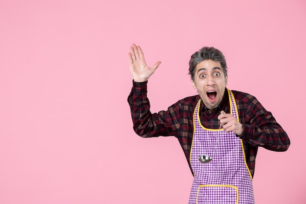 Vista frontal de los machos jóvenes en el cabo sosteniendo una cuchara de sopa de plata sobre fondo rosa trabajador profesión marido cocina cocinar alimentos horizontales