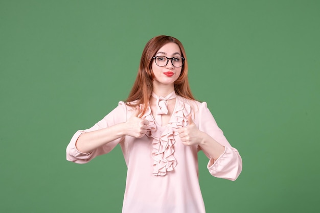 Vista frontal maestra en blusa rosa sobre fondo verde color trabajo libro estudiante joven lección escuela trabajo mujer