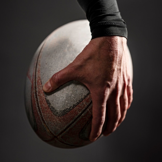 Vista frontal de la mano del jugador de rugby masculino sosteniendo la bola