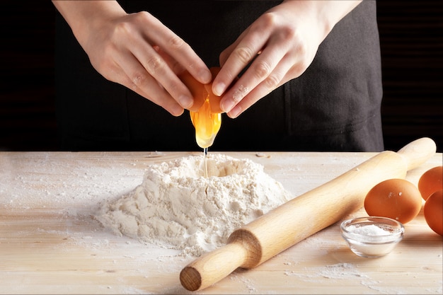 Vista frontal de las manos de mujer haciendo receta con rodillo de madera