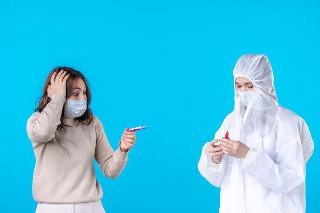 vista frontal médica em traje de proteção com paciente doente em um fundo azul claro vírus médico covid pandemia ciência saúde isolamento