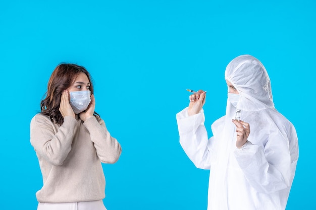 vista frontal médica em traje de proteção com paciente em fundo azul ciência pandêmica doença covid- vírus da saúde médico