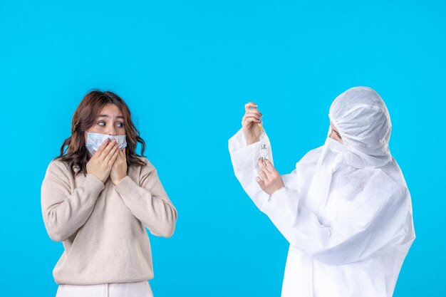 vista frontal médica em traje de proteção com paciente no fundo azul pandemia ciência doença covid- saúde isolamento vírus médico