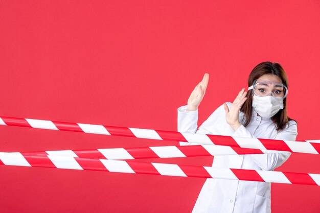 Foto vista frontal médica em uniforme médico e máscara em fundo vermelho