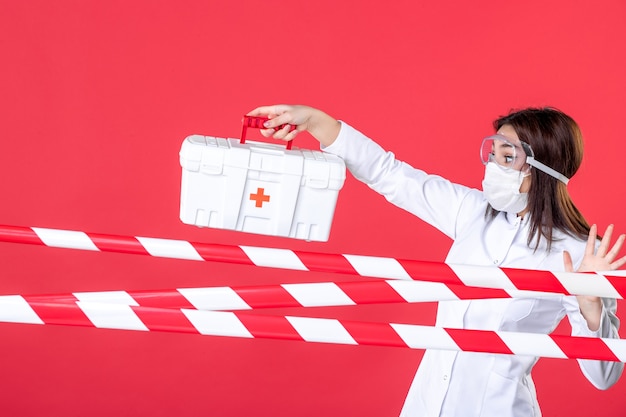 vista frontal médica segurando kit de primeiros socorros em fundo vermelho saúde linha covid vírus crime hospital perigo selado