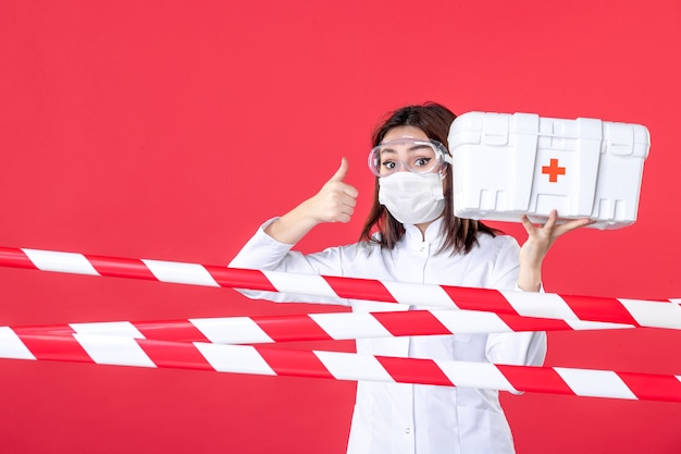Foto vista frontal médica segurando kit de primeiros socorros em fundo vermelho saúde linha covid vírus crime perigo selado cura