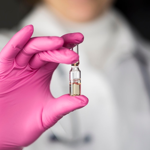 Foto vista frontal del médico con guante quirúrgico con medicamento