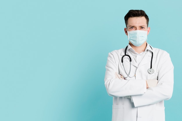 Foto vista frontal del médico con máscara médica posando con los brazos cruzados
