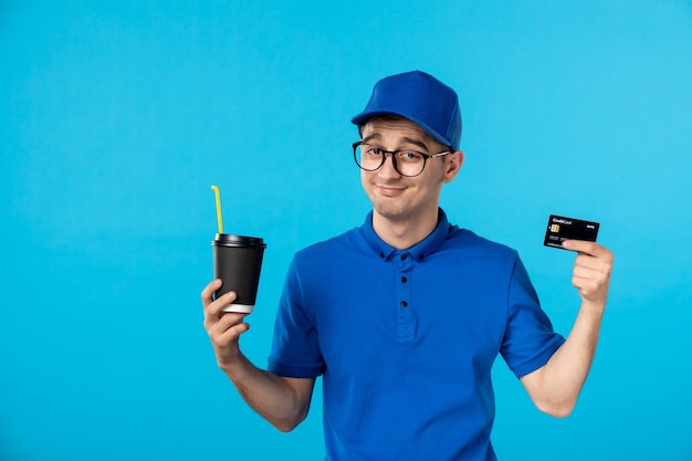 Vista frontal del mensajero masculino en uniforme azul con café y tarjeta de crédito en azul