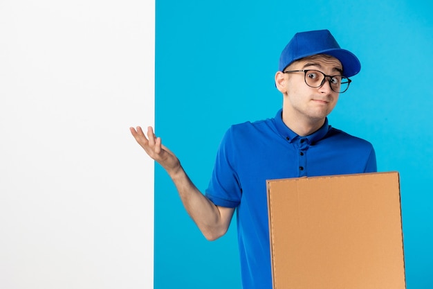 Vista frontal del mensajero masculino en uniforme azul con caja de pizza en azul