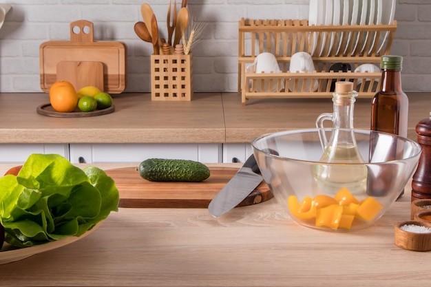 Vista frontal de la mesa de la cocina con ingredientes de ensalada, el fondo de una cocina moderna con utensilios domésticos en la encimera