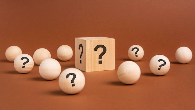 Vista frontal de muchos cubos de madera y bolas de madera con signos de interrogación, muchos conceptos que surgen de preguntas