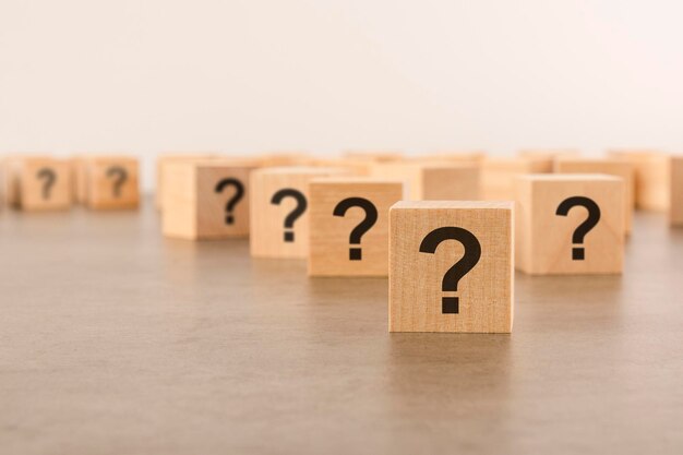 Vista frontal de muchos cubos de madera con signos de interrogación, muchos conceptos que surgen de preguntas