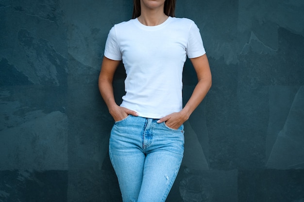 Vista frontal de la mujer en camiseta blanca maqueta en blanco y jeans azul sobre fondo gris