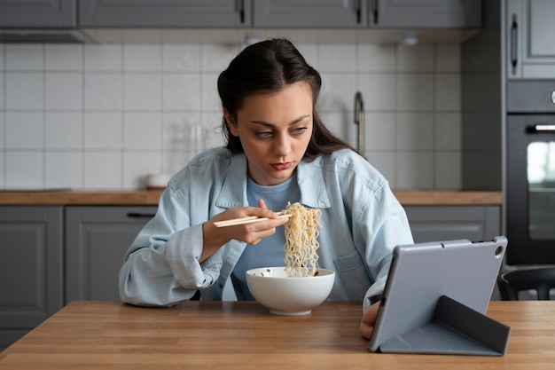 Foto vista frontal mujer comiendo con tableta