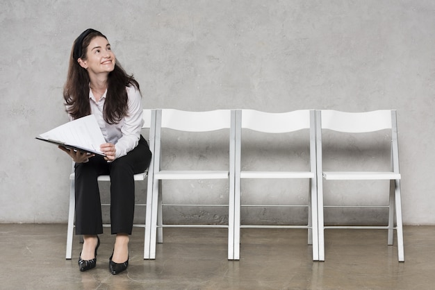 Vista frontal de la mujer esperando entrevista de trabajo con currículum