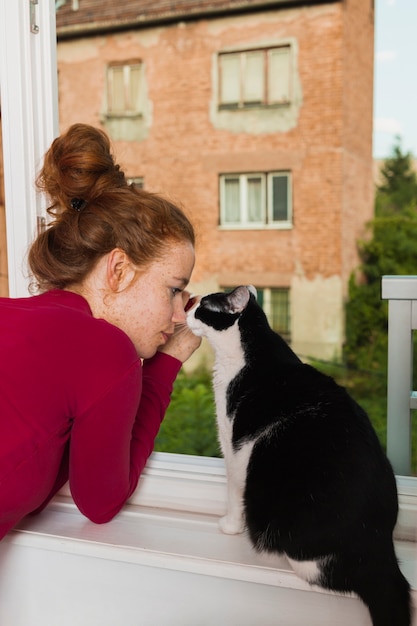 Foto vista frontal mujer y gato en el balcón