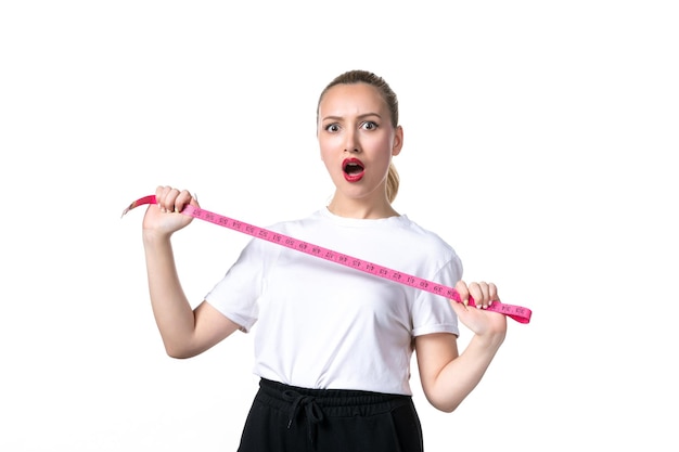 Vista frontal mujer joven con cinta métrica sobre fondo blanco cadera cintura peso piel escala perder medición torso adelgazamiento
