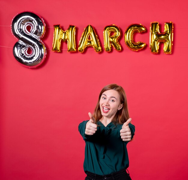 vista frontal mujer joven con decoración de marzo emocionado sobre fondo rojo presente amor moda glamour mujer día de la mujer sensual femenino regalo de vacaciones