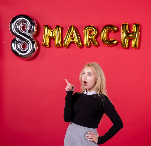 Vista frontal mujer joven con decoración de marzo sobre fondo rojo igualdad día de la mujer amor sensual pasión vacaciones salón femenino lujoso