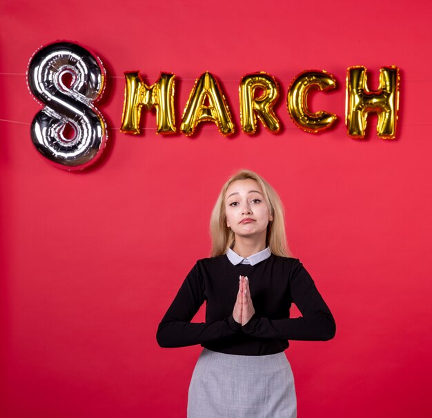 Vista frontal mujer joven con decoración de marzo sobre fondo rojo igualdad vacaciones día de la mujer amor lujoso pasión femenina sensual