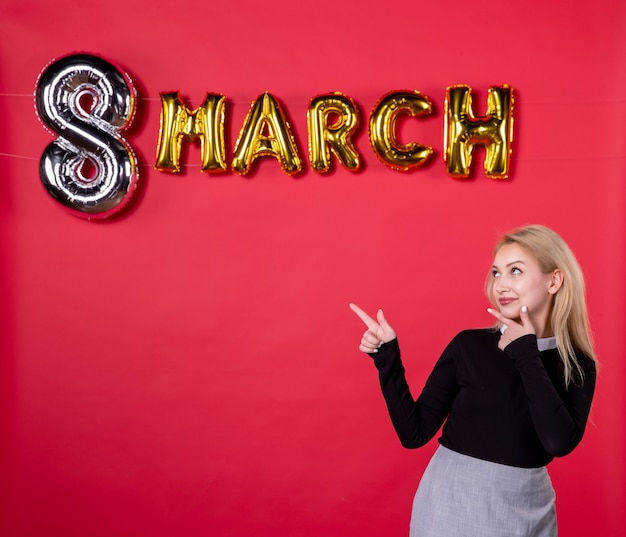 Vista frontal mujer joven con decoración de marzo sobre fondo rojo pasión salón amor lujoso día de la mujer sensual vacaciones igualdad