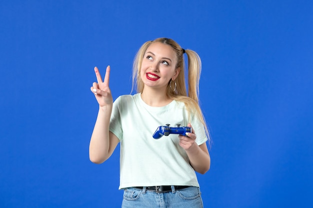 Vista frontal mujer joven con gamepad sobre fondo azul ganando video alegre en línea adulto jugador virtual juvenil