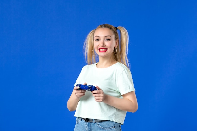 Vista frontal mujer joven con gamepad sobre fondo azul video en línea para adultos ganador de Internet virtual alegre jugador de sofá