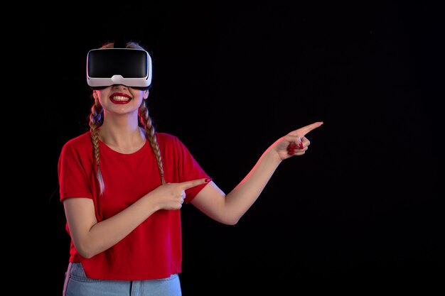 Vista frontal de la mujer joven jugando vr en la pared oscura