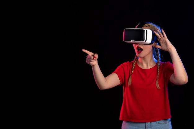 Vista frontal de la mujer joven jugando vr en la pared oscura