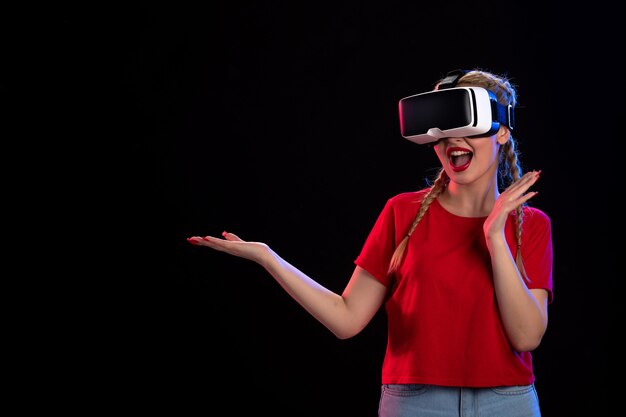 Vista frontal de la mujer joven jugando vr en la pared oscura