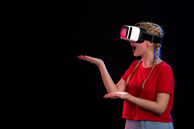 Vista frontal de la mujer joven jugando vr en la pared oscura