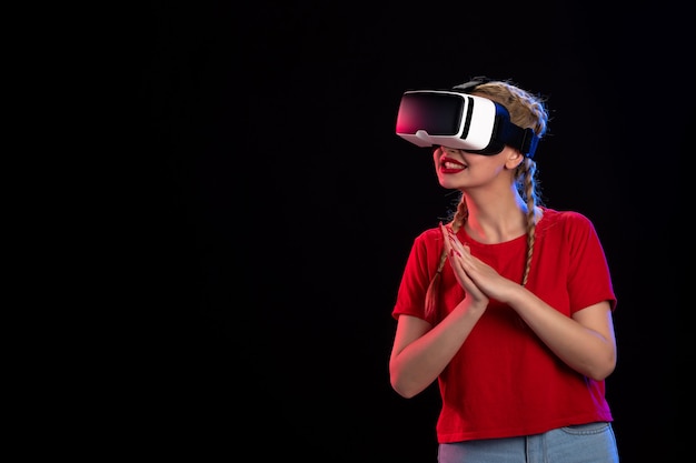 Vista frontal de la mujer joven jugando vr en la pared oscura