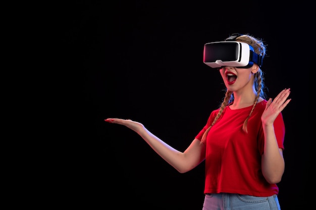 Vista frontal de la mujer joven jugando vr en la pared oscura