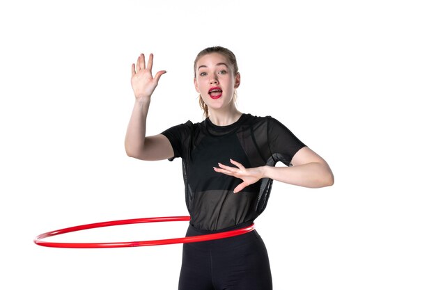 Vista frontal mujer joven que trabaja con hula hoop rojo sobre fondo blanco atleta deporte mujer salud cuerpo yoga