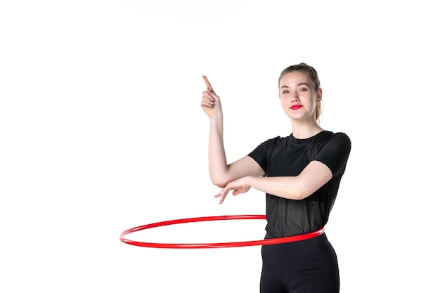Vista frontal mujer joven que trabaja con hula hoop rojo sobre fondo blanco color estilo de vida atleta mujer salud cuerpo yoga deporte