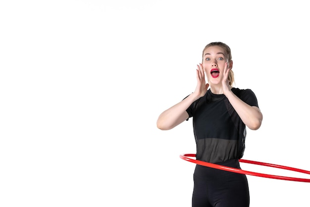 Vista frontal mujer joven que trabaja con hula hoop rojo sobre fondo blanco color estilo de vida atleta mujer salud cuerpo yoga