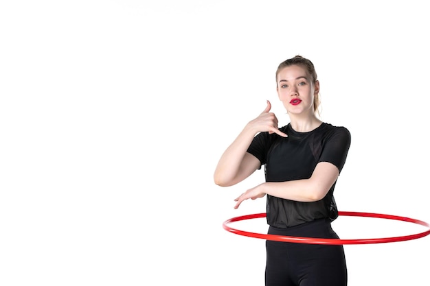 Vista frontal mujer joven que trabaja con hula hoop rojo sobre fondo blanco color estilo de vida mujer salud cuerpo yoga deporte atleta