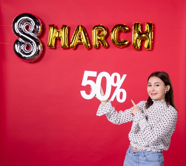 Vista frontal mujer joven sosteniendo la escritura sobre fondo rojo dinero moda mujer centro comercial vacaciones igualdad cariñosa belleza compras